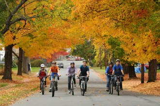 Group of adults and children biking on a street overhung by fall foliage. Image credit: Paul Franz, The Recorder